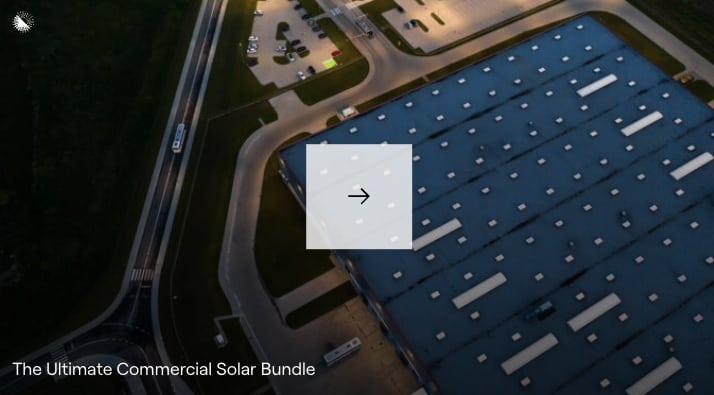 Aerial view of a commercial building with rooftop solar panels at twilight