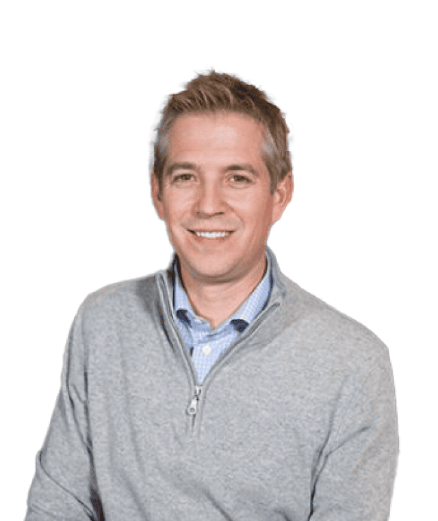 A smiling man in a grey half-zip sweater over a collared shirt.